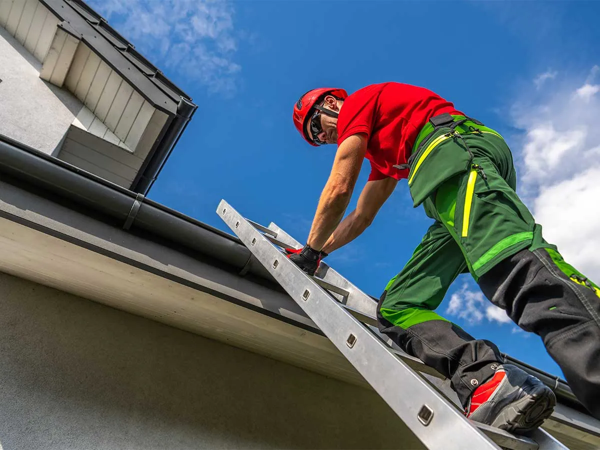 Gutter installation technician working from a ladder